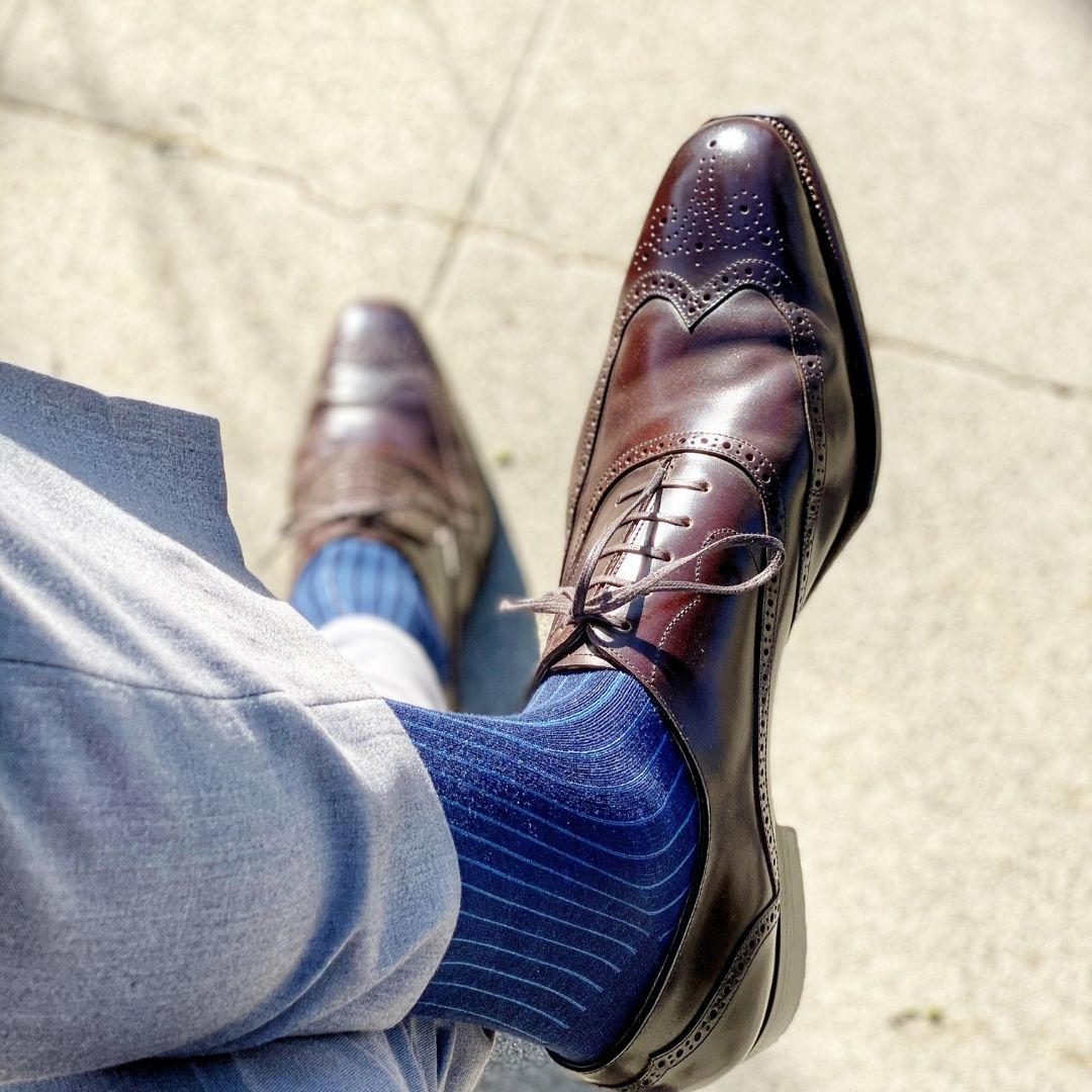 Man wearing midnight blue, solid, ribbed men's dress socks with brown shoes.