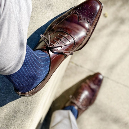 Man wearing midnight blue, solid, ribbed men's dress socks with brown shoes and grey slacks.