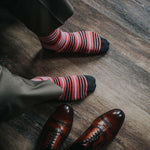 Man wearing coral, grey and white striped socks and dress shoes