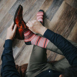 Man wearing coral, grey and white striped socks and dress shoes