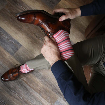 Man wearing coral, grey and white striped socks and dress shoes