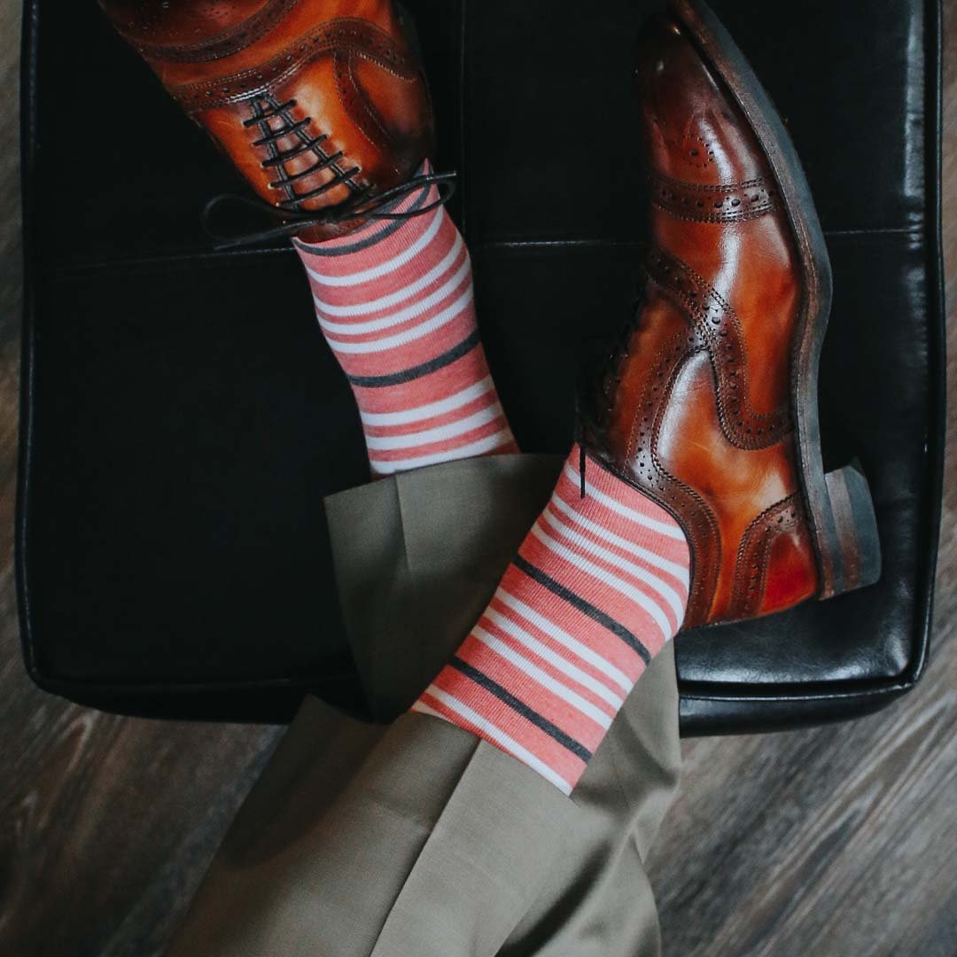 Man wearing coral, grey and white striped socks and dress shoes