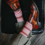 Man wearing coral, grey and white striped socks and dress shoes