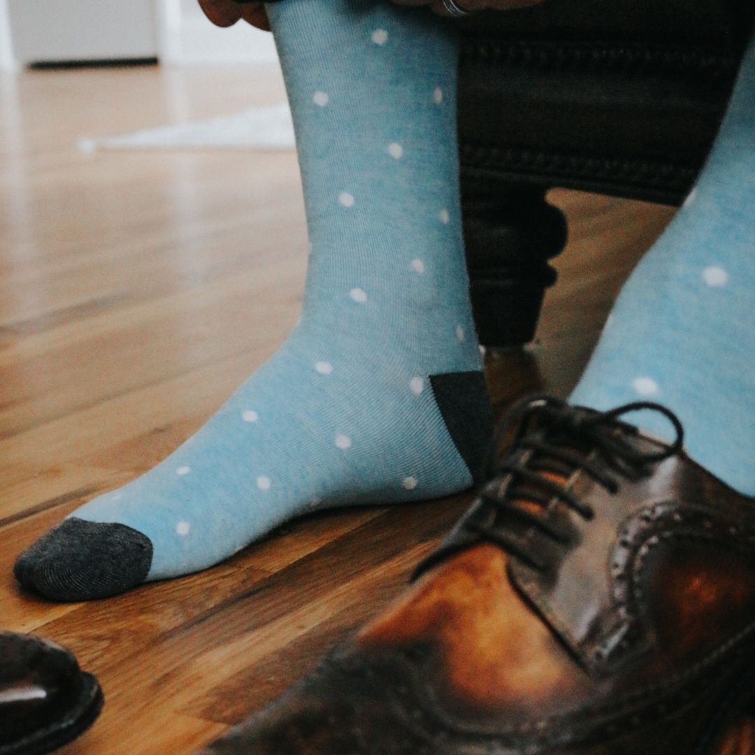 Man wearing baby blue and white polka dot socks, and dress shoes.