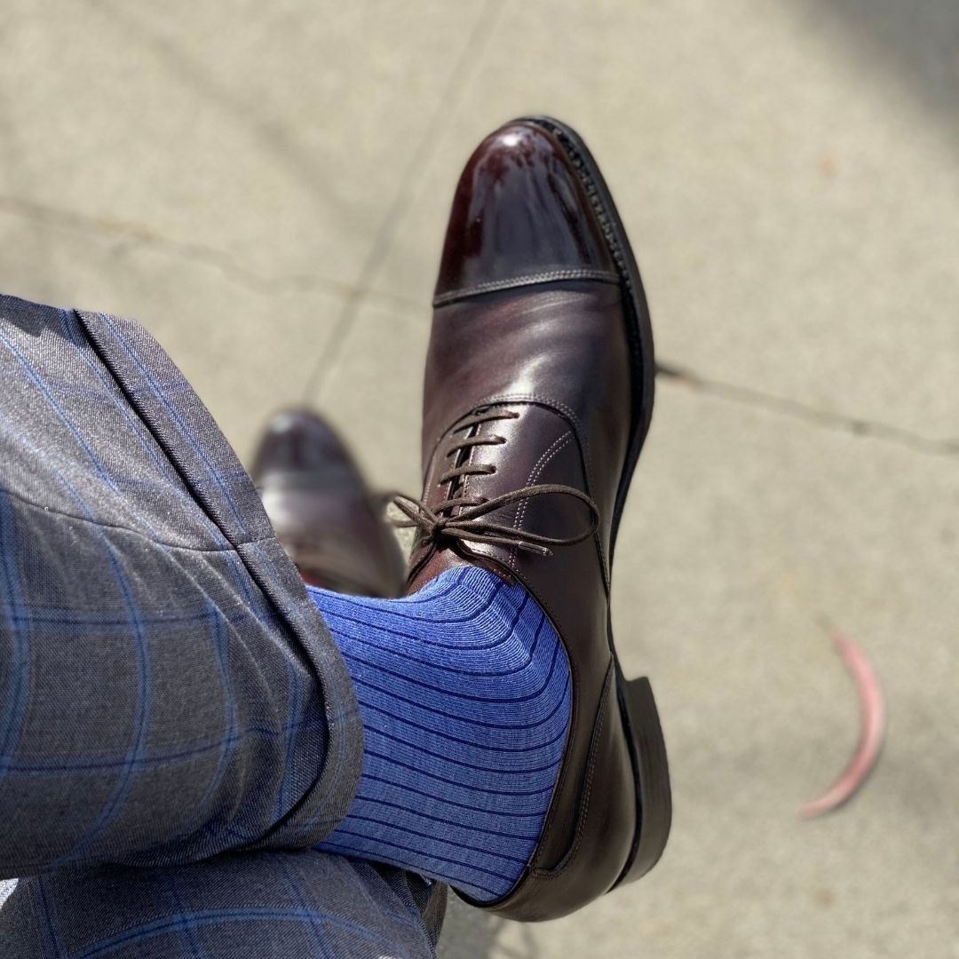 Man wearing solid, blue, and navy blue ribbed men's dress socks and shoes.