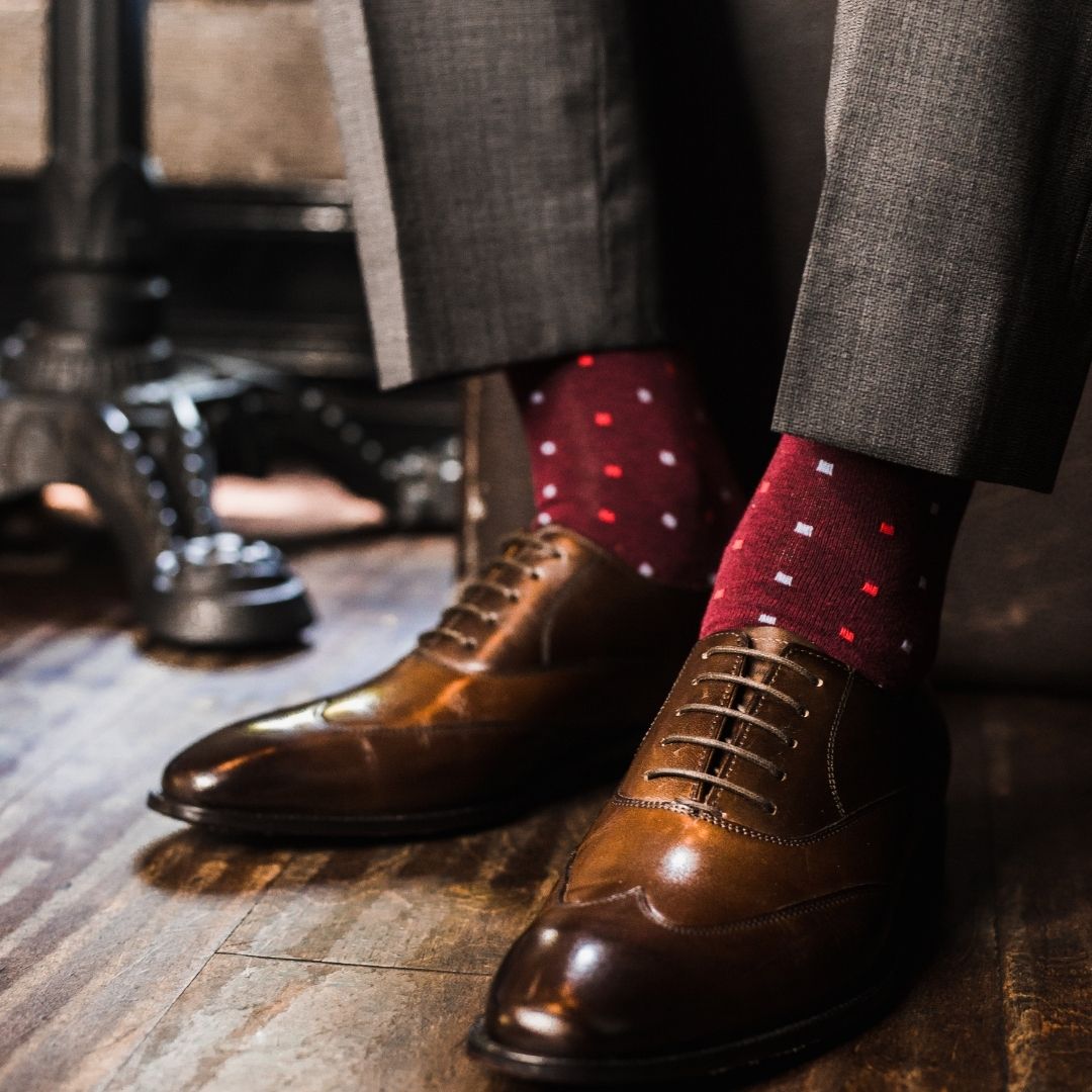 Man wearing cranberry socks with red and powder blue micro-squares