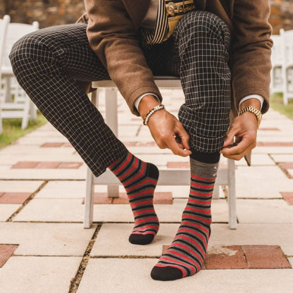 Man wearing charcoal grey, red, and black striped sock