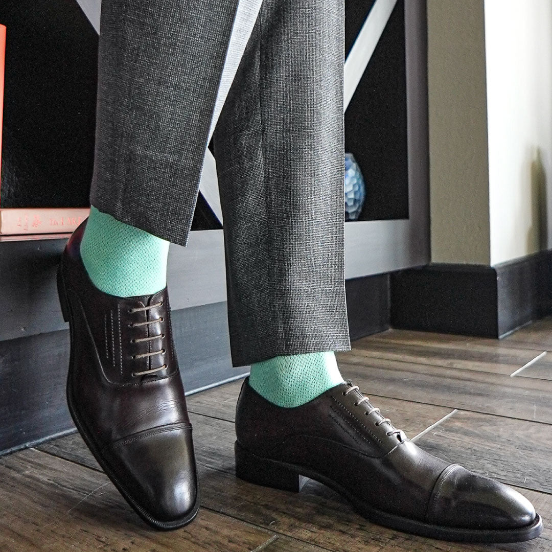 Man wearing seafoam green men's dress socks with grey slacks