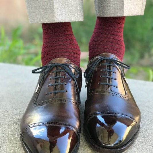 A man wearing burgundy socks and brown shoes