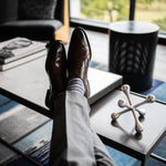 a man wearing grey, blue, and white striped men's dress socks with brown shoes and grey slacks