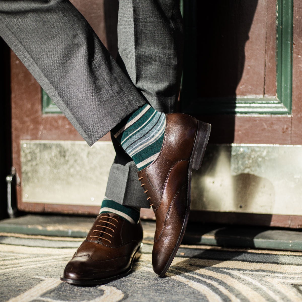 Man wearing green, taupe, and tan striped socks with dress shoes
