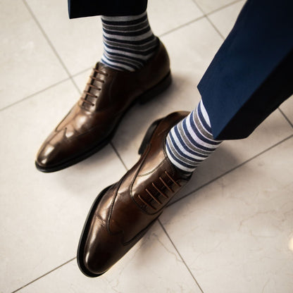 a guy wearing gray, blue, and white striped men's dress socks with brown shoes