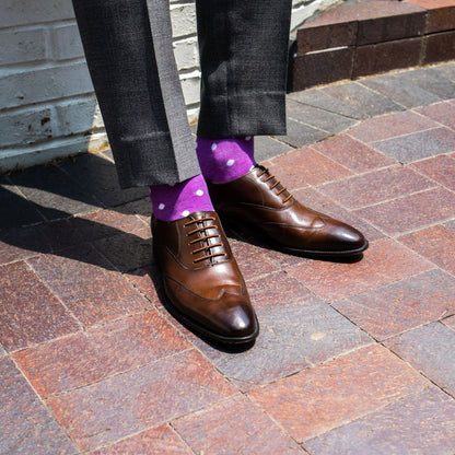 guy wearing lilac purple sock with white polka dots with grey pants