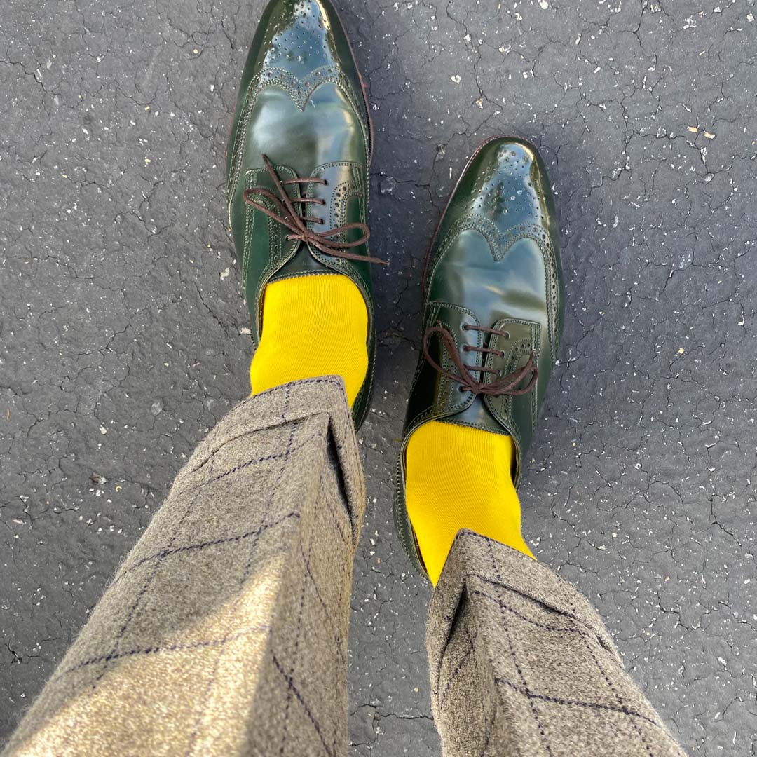 Man standing wearing canary yellow men's dress socks and shoes.