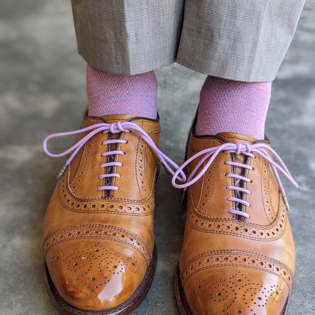Man wearing pink socks, and brown shoes.