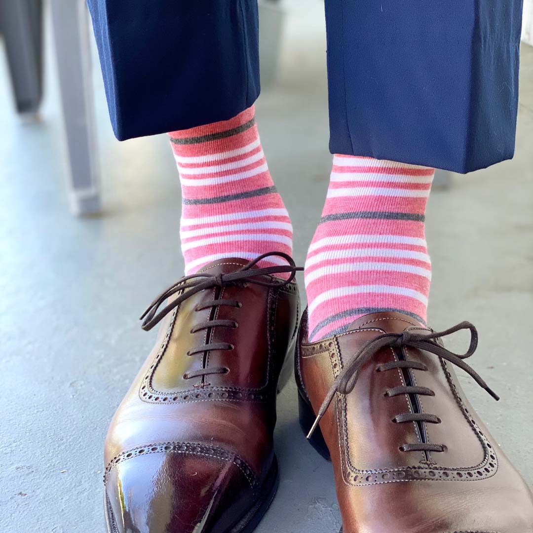 Man wearing coral, grey and white striped socks and dress shoes