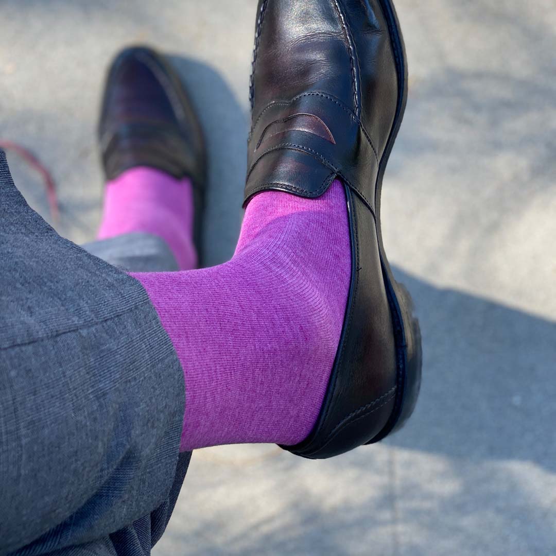 Man sitting with legs crossed wearing fuchsia men's dress socks and brown shoes