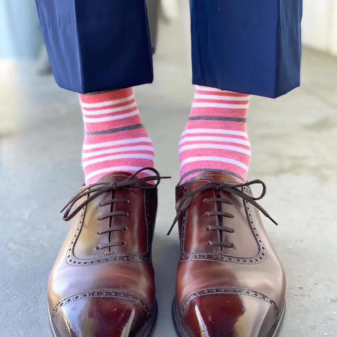 Man wearing coral, grey and white striped socks and dress shoes