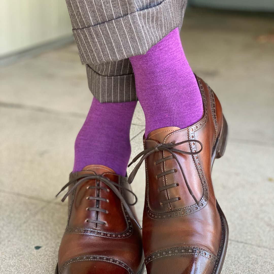 Man standing with feet crossed wearing plum purple men's dress socks and shoes.
