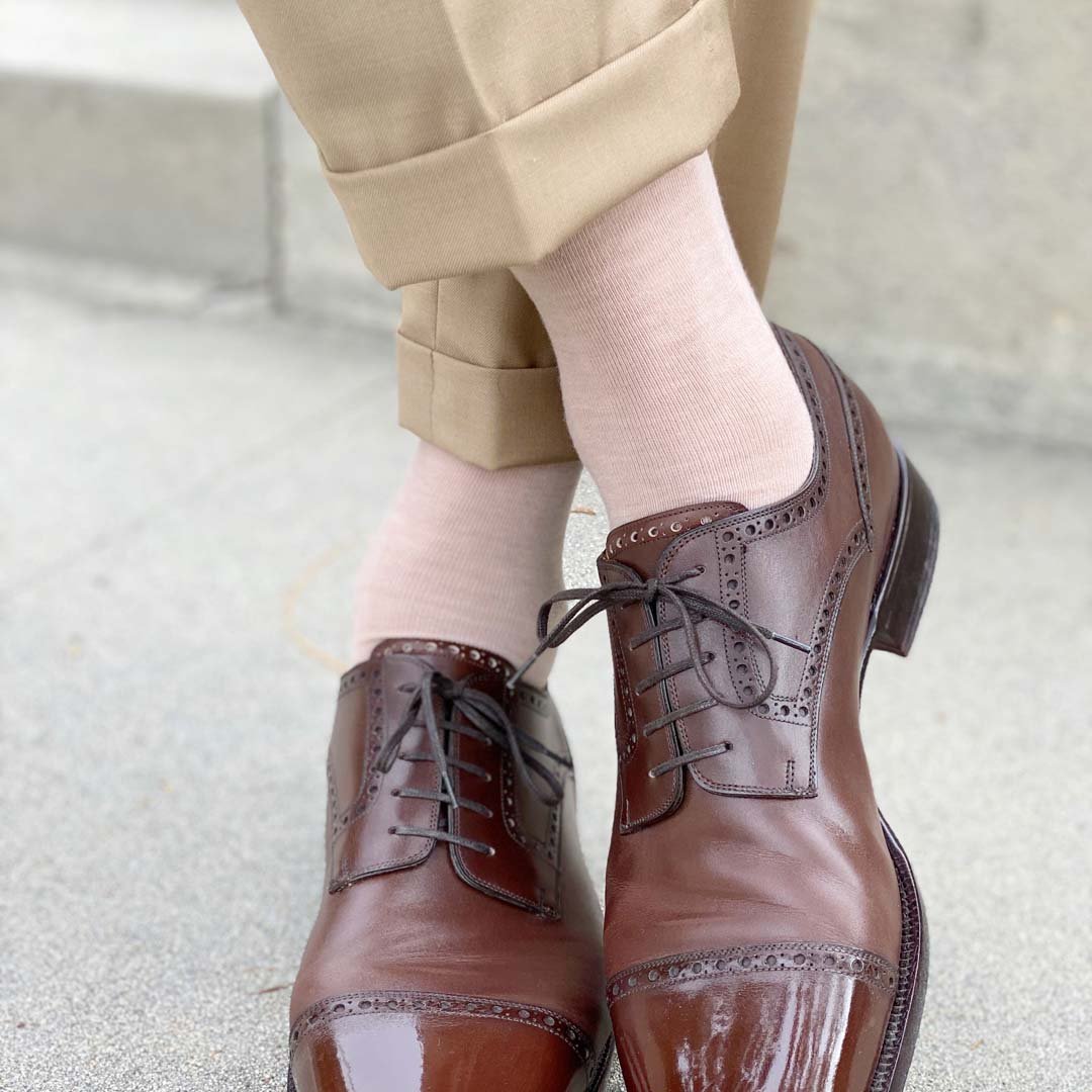 Man standing with feet crossed wearing slacks, oatmeal men's dress socks and brown shoes.