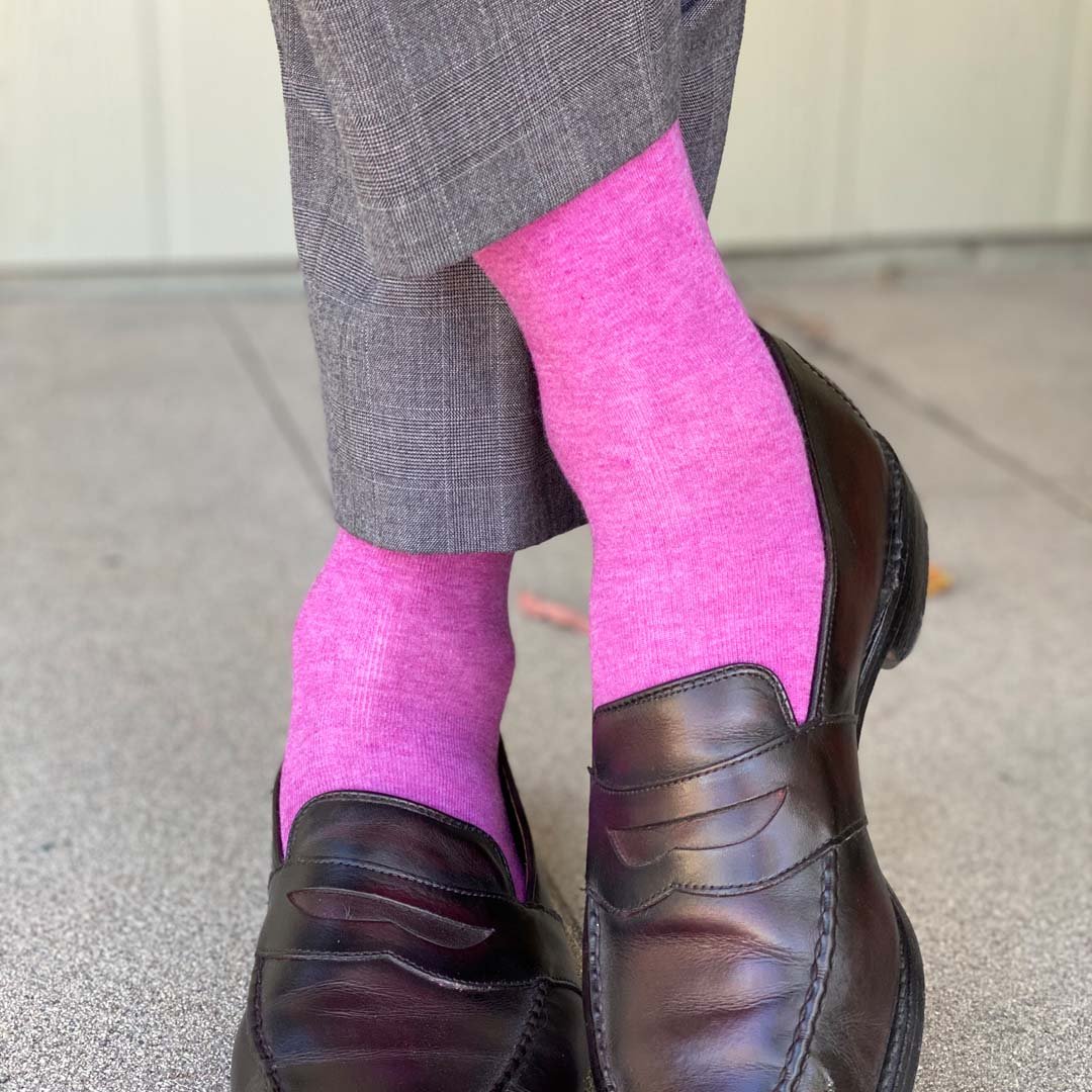 Man standing with feet crossed wearing fuchsia men's dress socks and brown shoes
