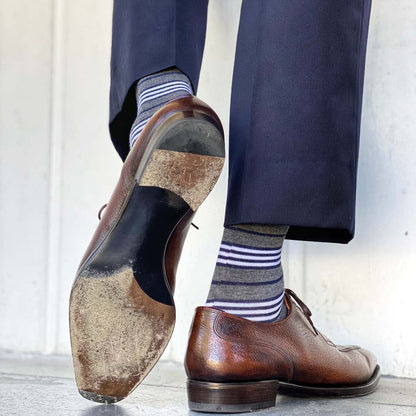 Man wearing gray, white and blue stripe socks with brown shoes