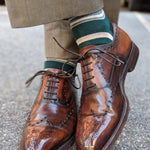 Man wearing green, taupe, and tan striped socks with dress shoes