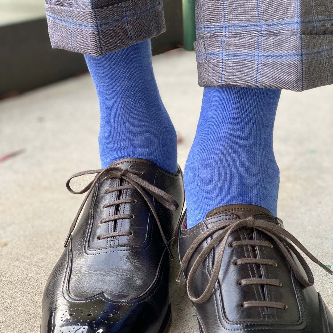 Man standing wearing steel blue men's dress socks, and black shoes.
