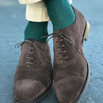 Man standing with feet crossed wearing hunter green socks and dress shoes