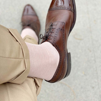 Man sitting with legs crossed wearing slacks, oatmeal men's dress socks and brown shoes.