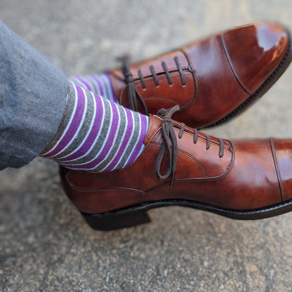 Man wearing purple, grey, and white striped dress socks and brown dress shoes
