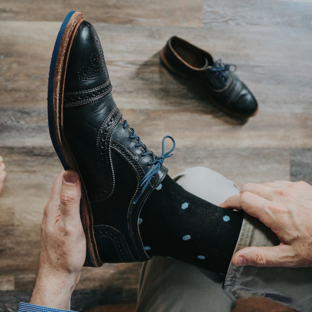 Man wearing black socks with blue polka dots and dress shoes
