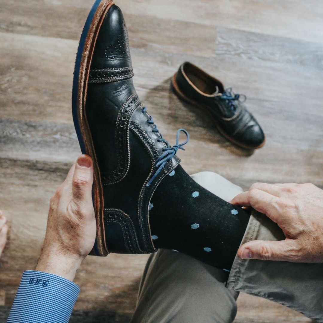 Man wearing black socks with blue polka dots and dress shoes