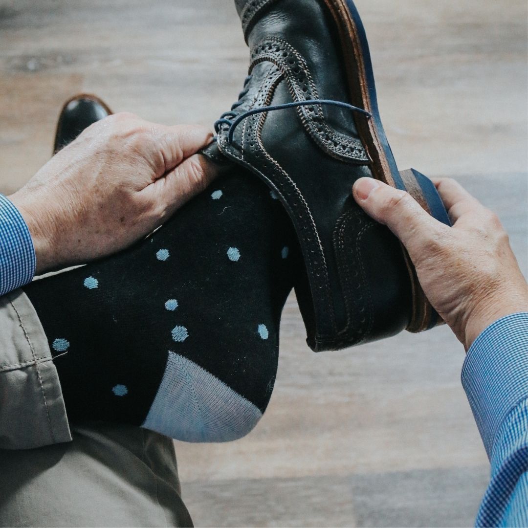 Man wearing black socks with blue polka dots and dress shoes