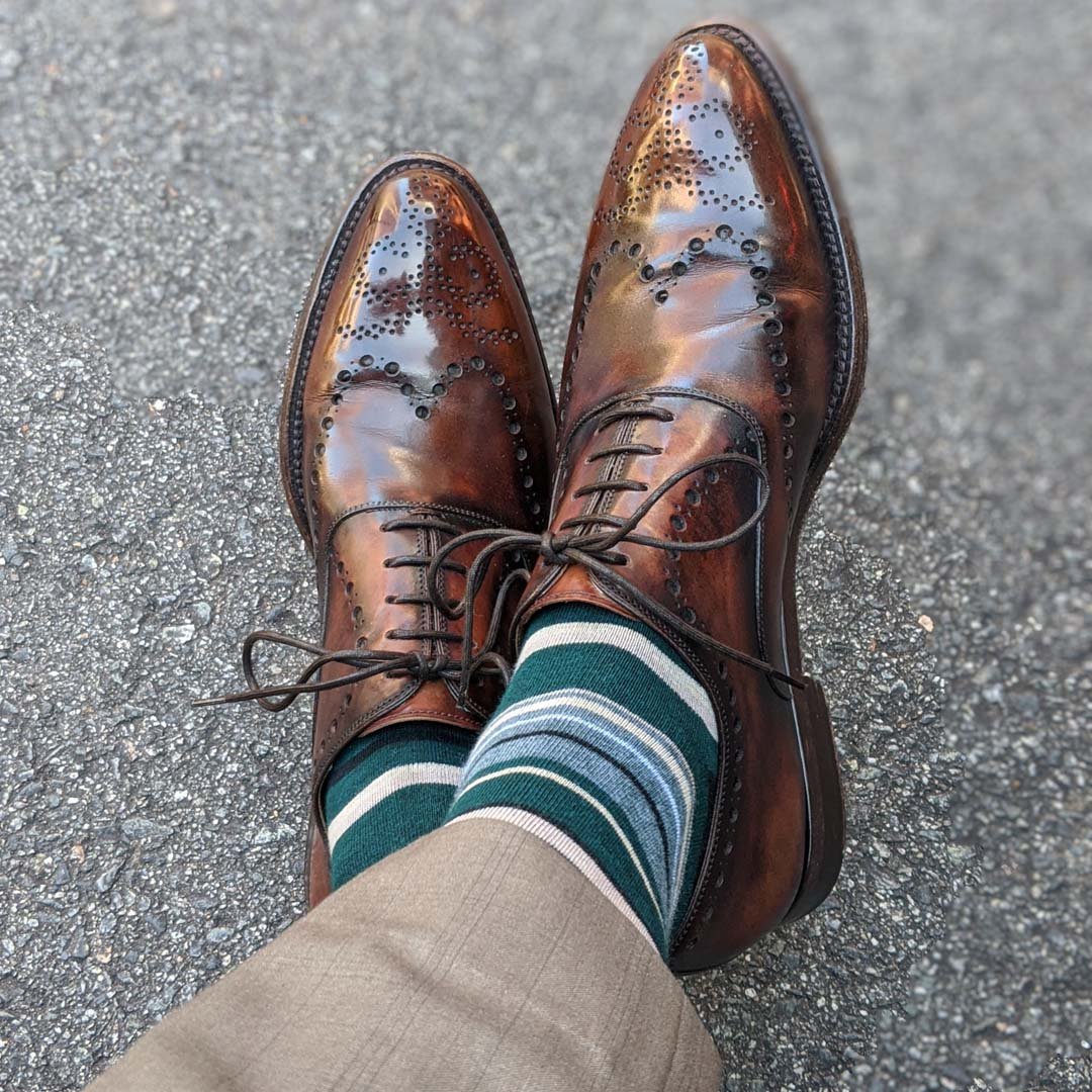 Man wearing green, taupe, and tan striped socks with dress shoes
