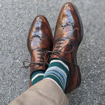 Man wearing green, taupe, and tan striped socks with dress shoes
