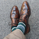 Man wearing green, taupe, and tan striped socks with dress shoes