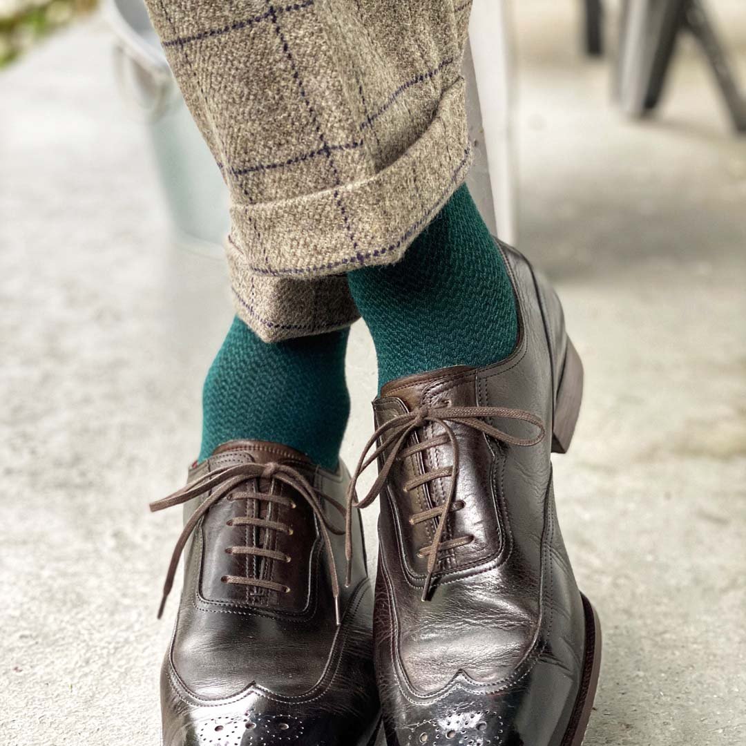  Man standing with feet crossed wearing hunter green socks and dress shoes