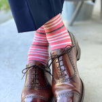 Man wearing coral, grey and white striped socks and dress shoes