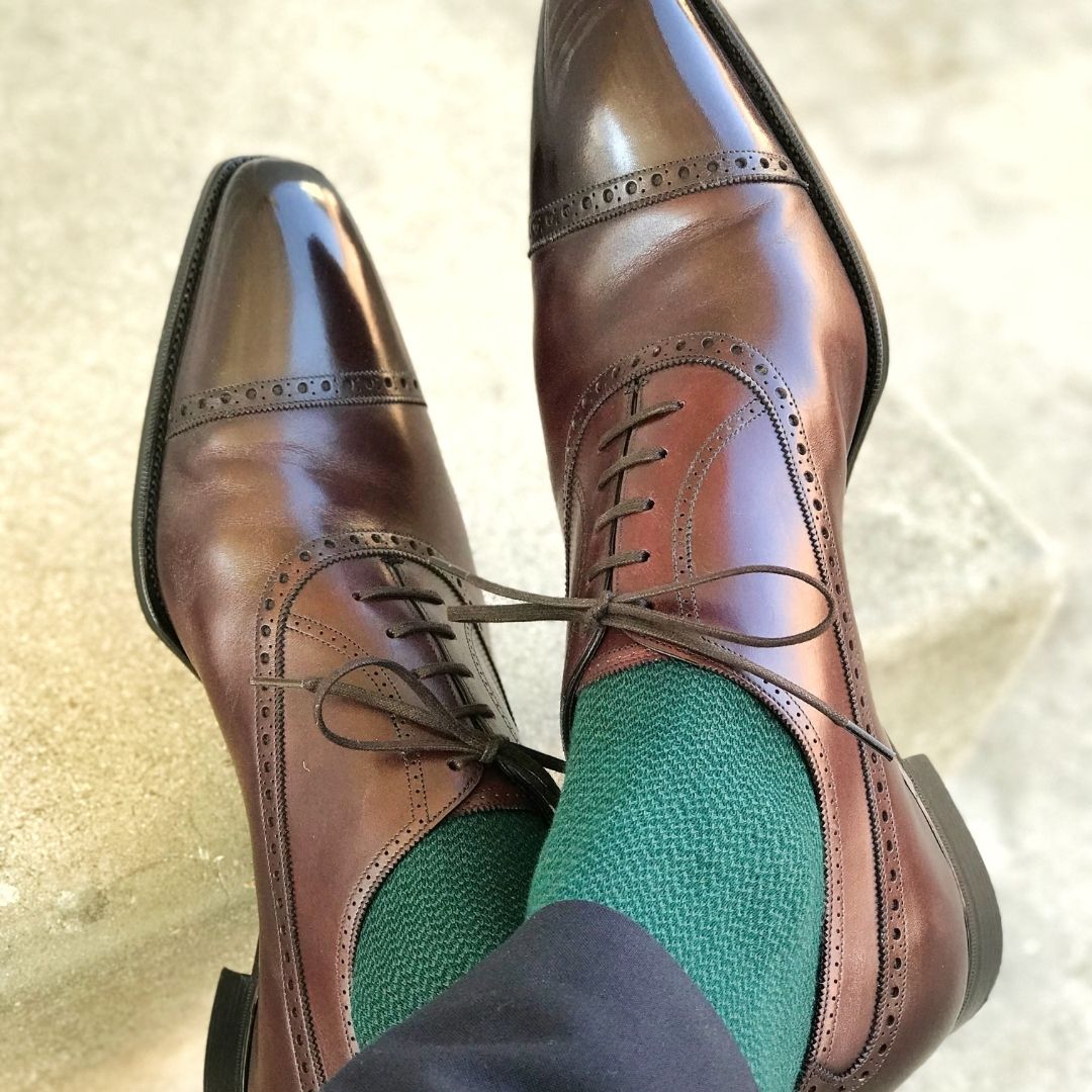 Man sitting with legs crossed wearing hunter green socks and dress shoes