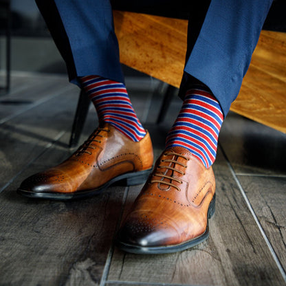 man wearing red, white, and blue dress socks with blue trousers and tan shoes.