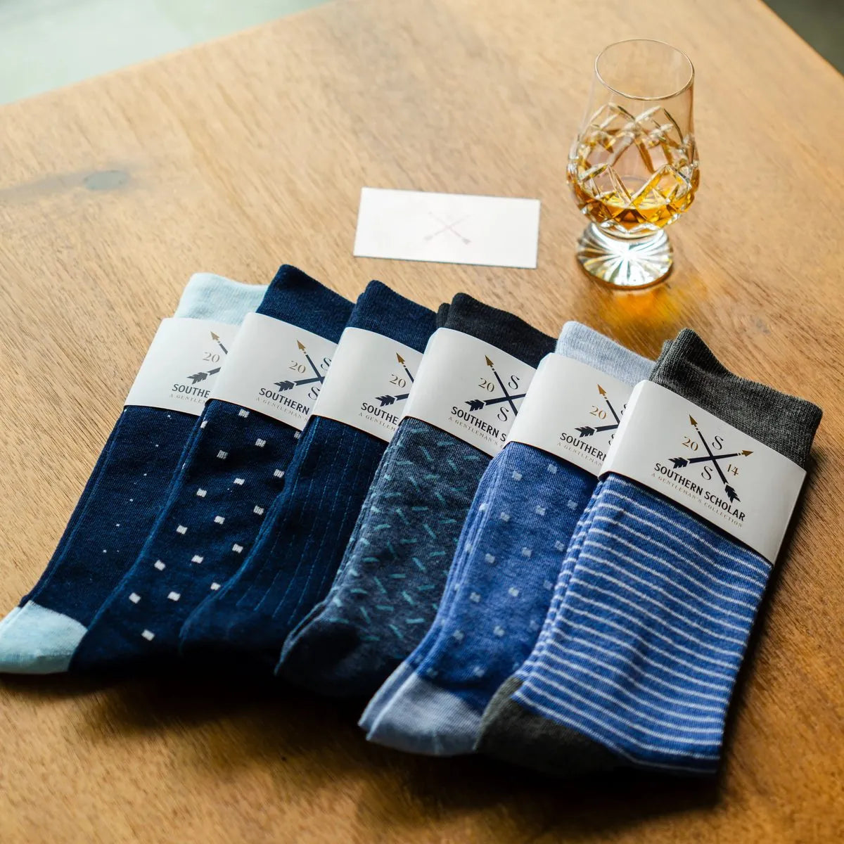 Flat lay of all six Blue Bundle socks with a whiskey glass
